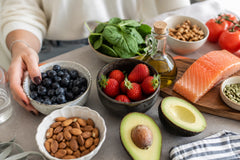 Alimentos buenos para la piel: bodegón con arándanos, fresas, almendras, aguacate, salmón, espinacas y nueces