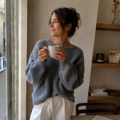 Mujer relajada sujetando una taza junto a la ventana con luz natural